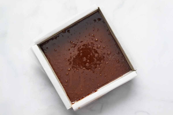 Unbaked brownie batter in a parchment-lined square cake pan.