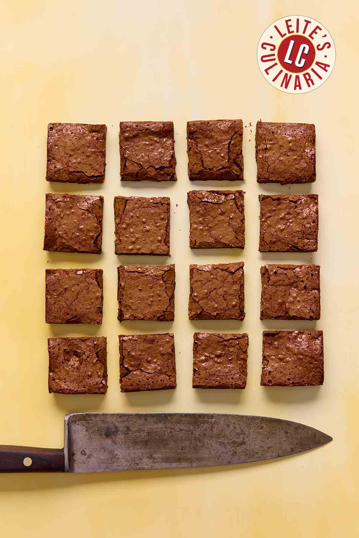 Sixteen square brownies on a yellow background.