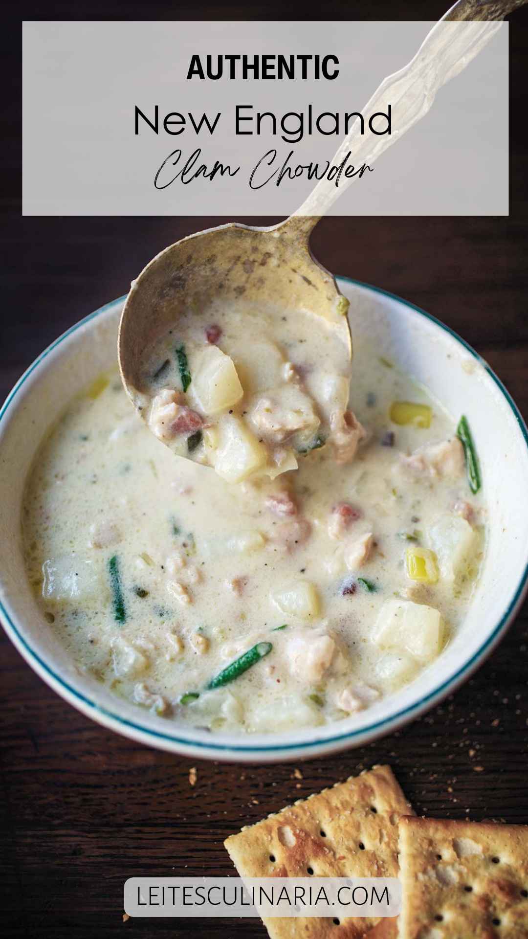 A bowl of New England clam chowder with a spoon scooping some out.