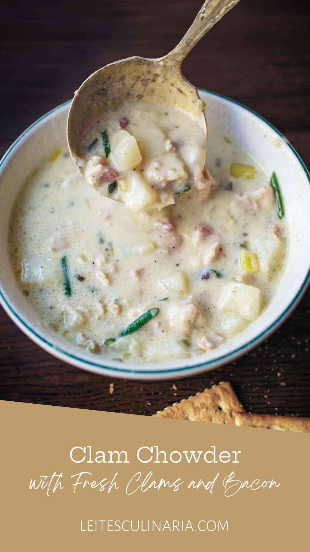 A bowl of New England clam chowder with a spoon scooping some out.