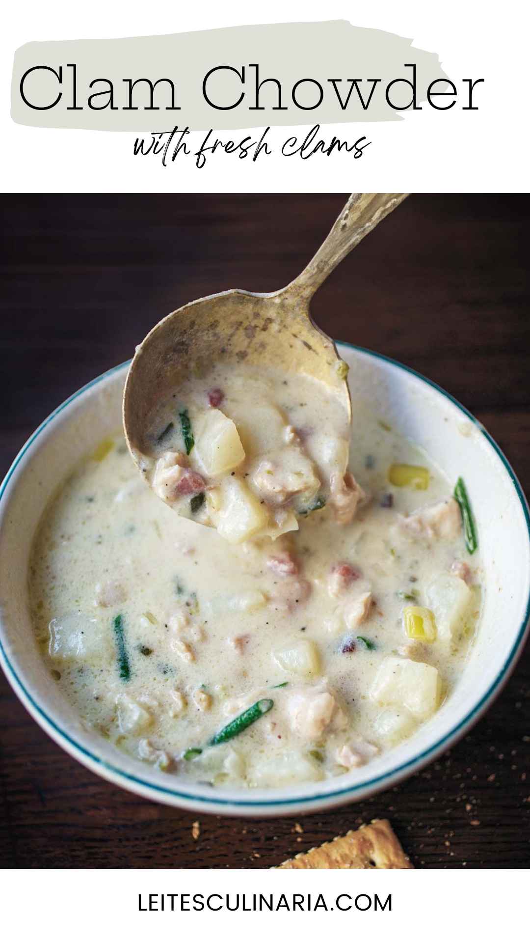 A bowl of New England clam chowder with a spoon scooping some out.