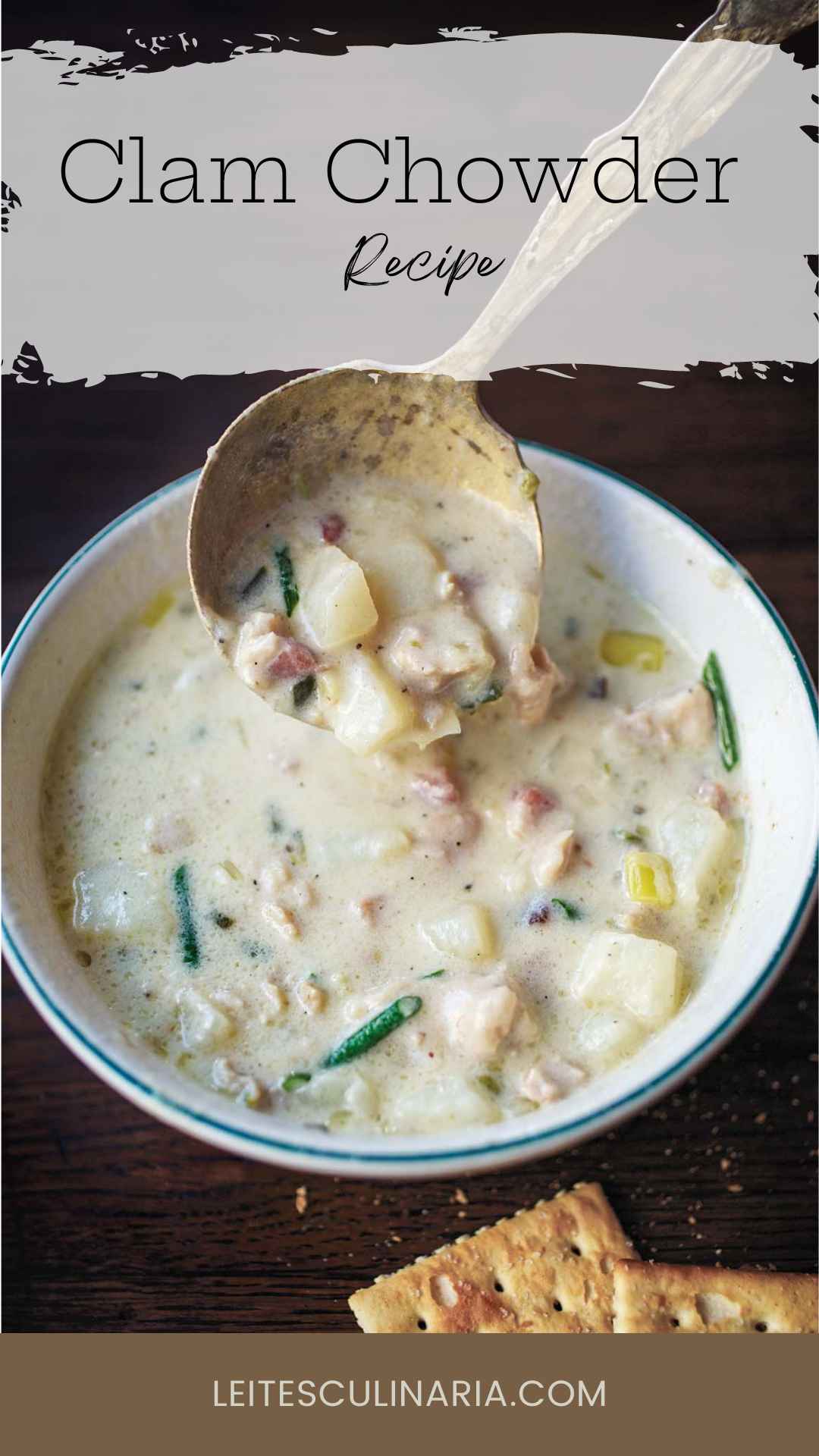 A bowl of New England clam chowder with a spoon scooping some out.