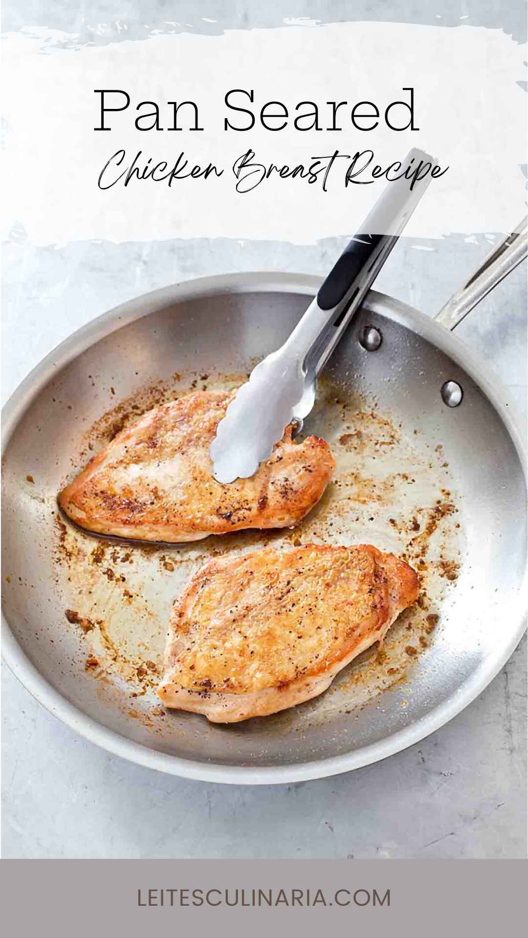 Two crispy pan seared chicken breasts in a metal skillet with a set of tongs.