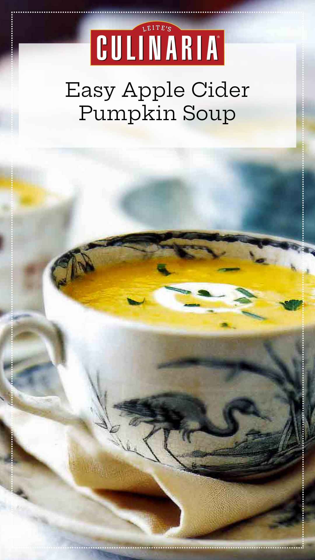 A large teacup filled with pumpkin cider soup with a swirl of creme fraiche and some herbs sprinkled on top.