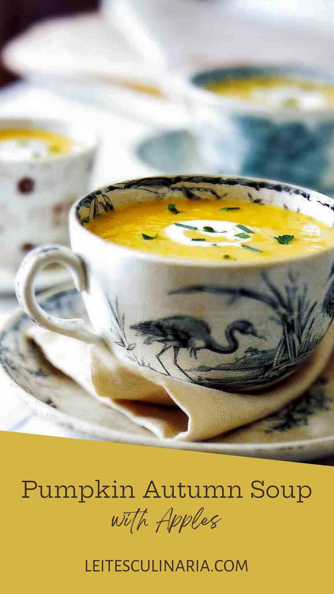 A large teacup filled with pumpkin cider soup with a swirl of creme fraiche and some herbs sprinkled on top.