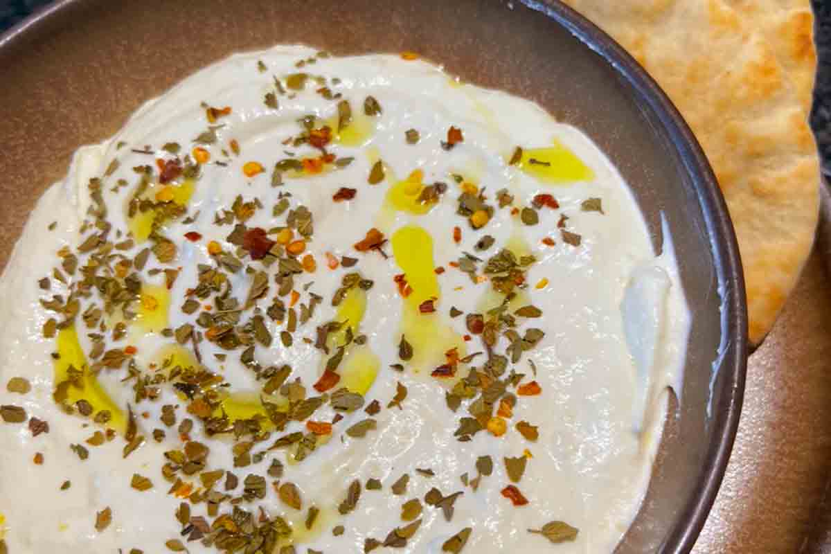 A bowl of creamy whipped feta dip topped with oil and dried herbs.