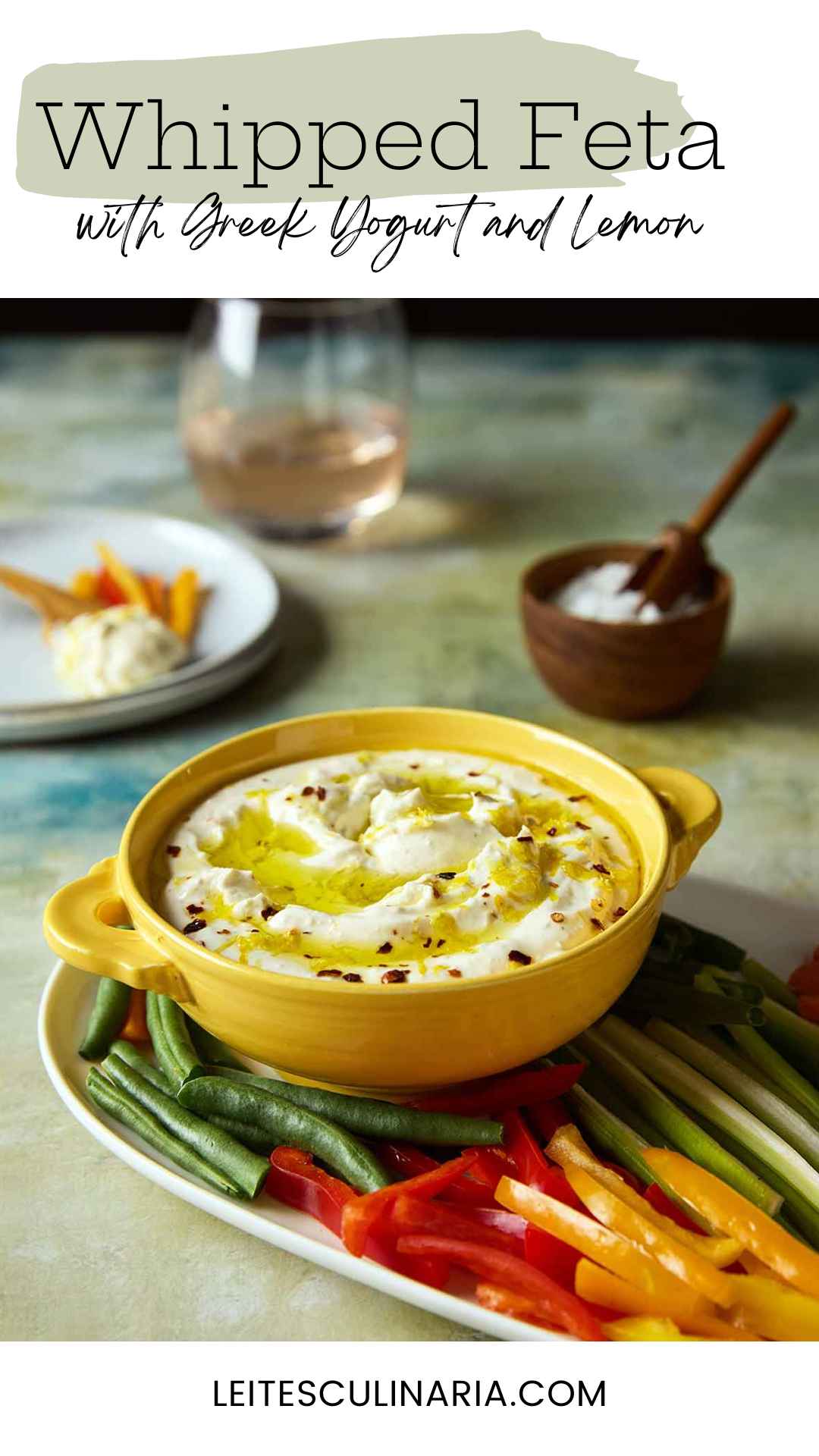 A bowl of whipped feta dip topped with oil and lemon zest on a platter of raw vegetables.