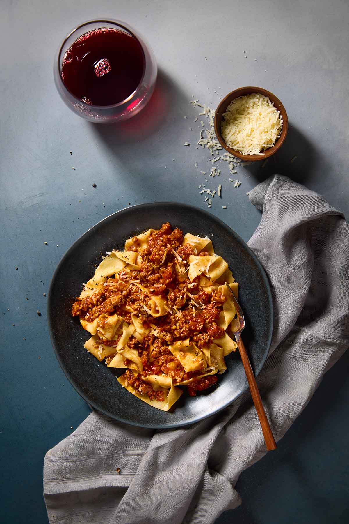 A black plate filled with Marcella Hazan's Bolognese sauce over homemade tagliatelle.