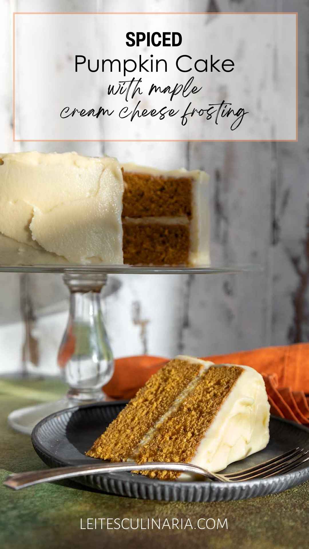 A slice of frosted pumpkin cake on a plate with the remaining cake on a stand in the background.