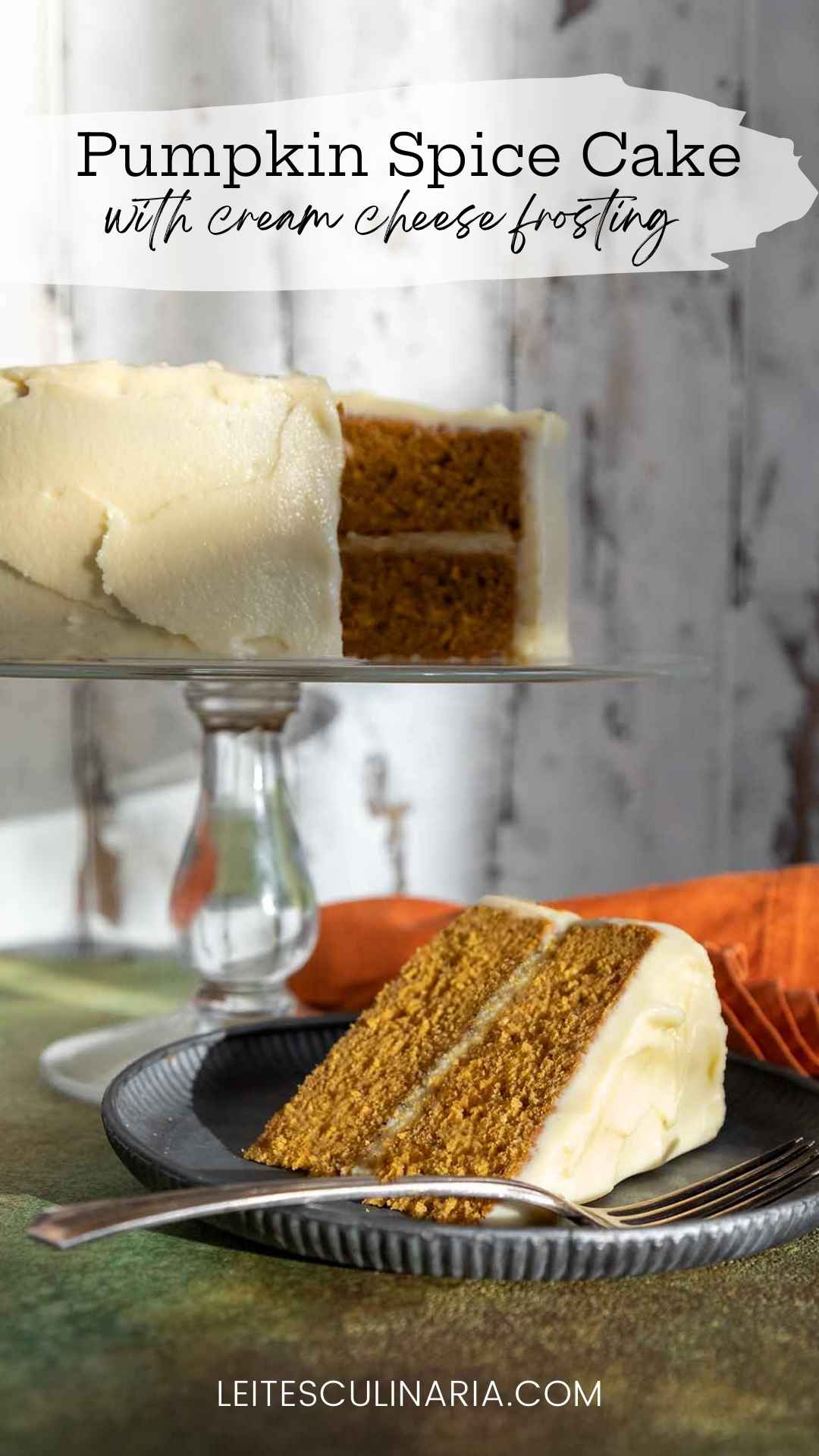 A slice of frosted pumpkin cake on a plate with the remaining cake on a stand in the background.