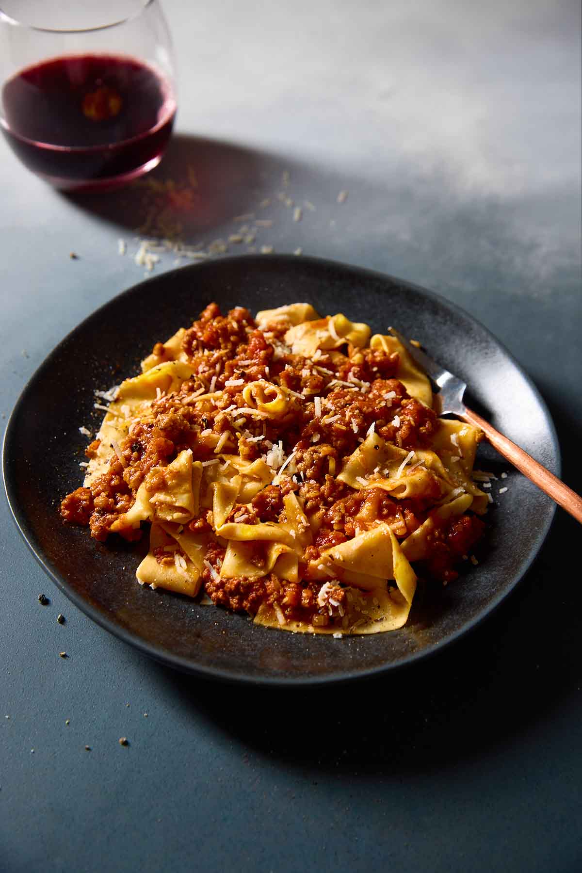 A black plate filled with Marcella Hazan's Bolognese sauce over homemade tagliatelle.