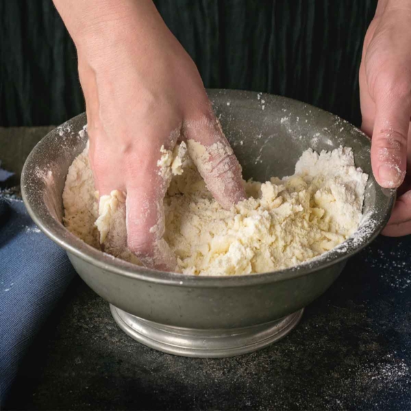 Shortcut pie crust being mixed together by hand in a bowl.