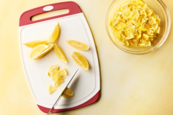 A man's hand cutting Meyer lemons in quarters.