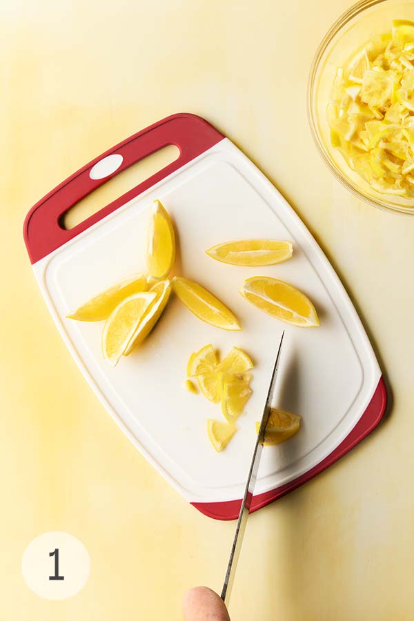 A person cutting Meyer lemons in quarters.