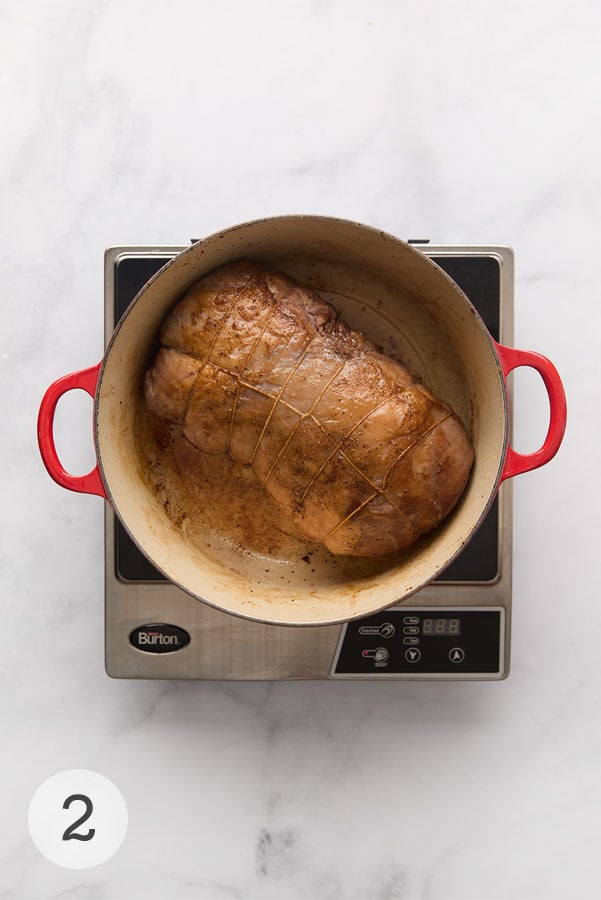 A seared boneless leg of lamb in a Dutch oven.