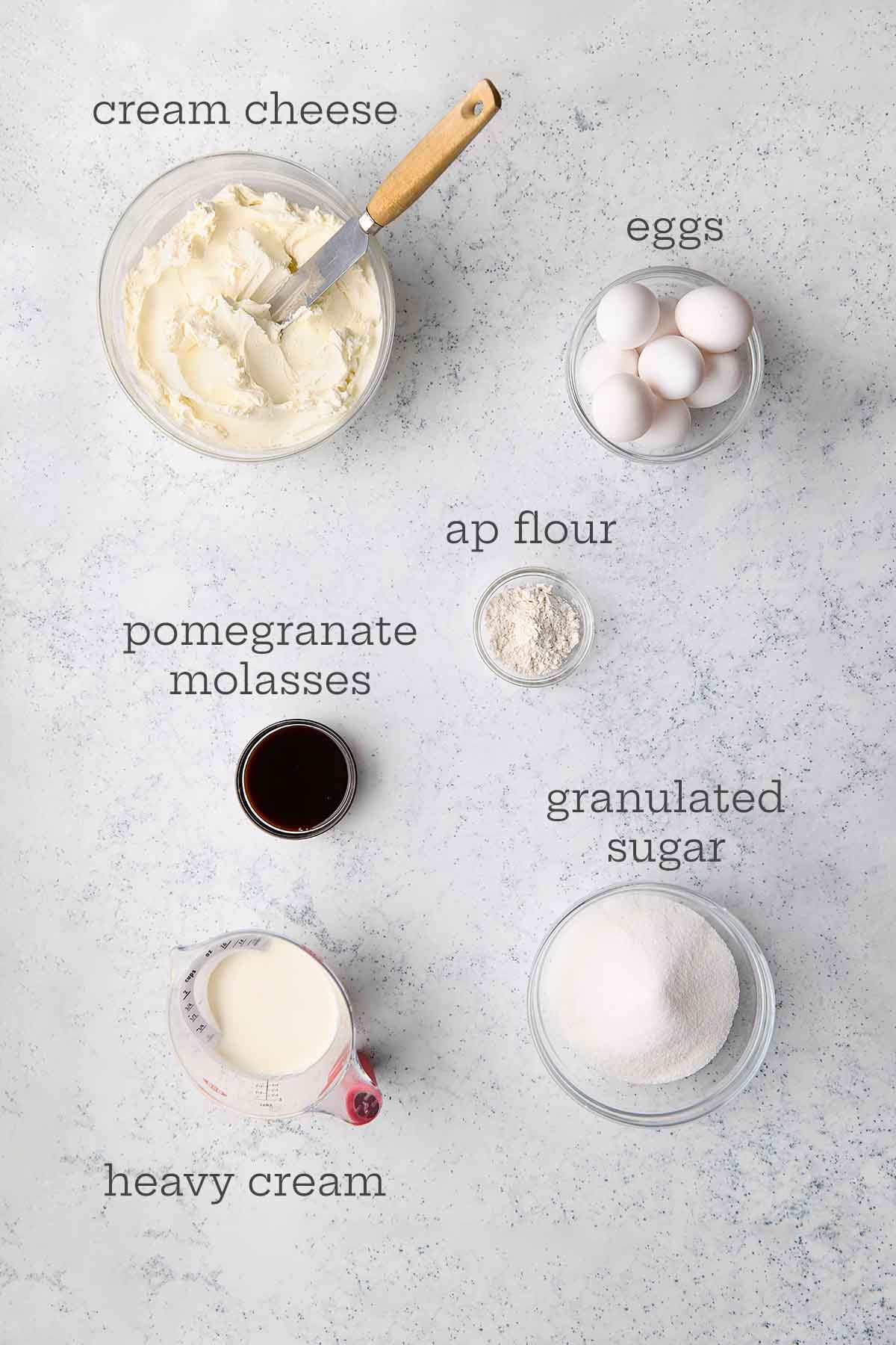 The ingredients for a pomegranate San Sebastian Basque cheesecake: cream cheese, eggs, all purpose flour, granulated sugar, heavy cream, and pomegranate molasses.