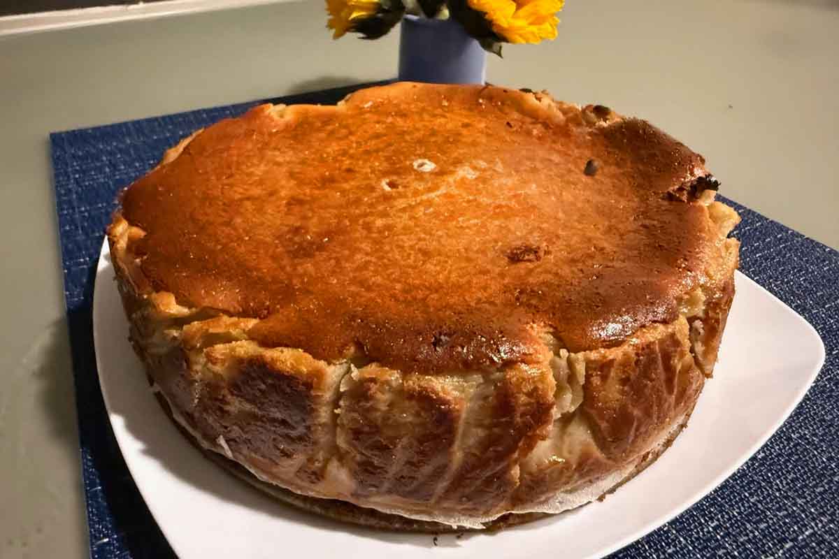 A San Sebastian burnt Basque cheesecake with pomegranate on a white platter.