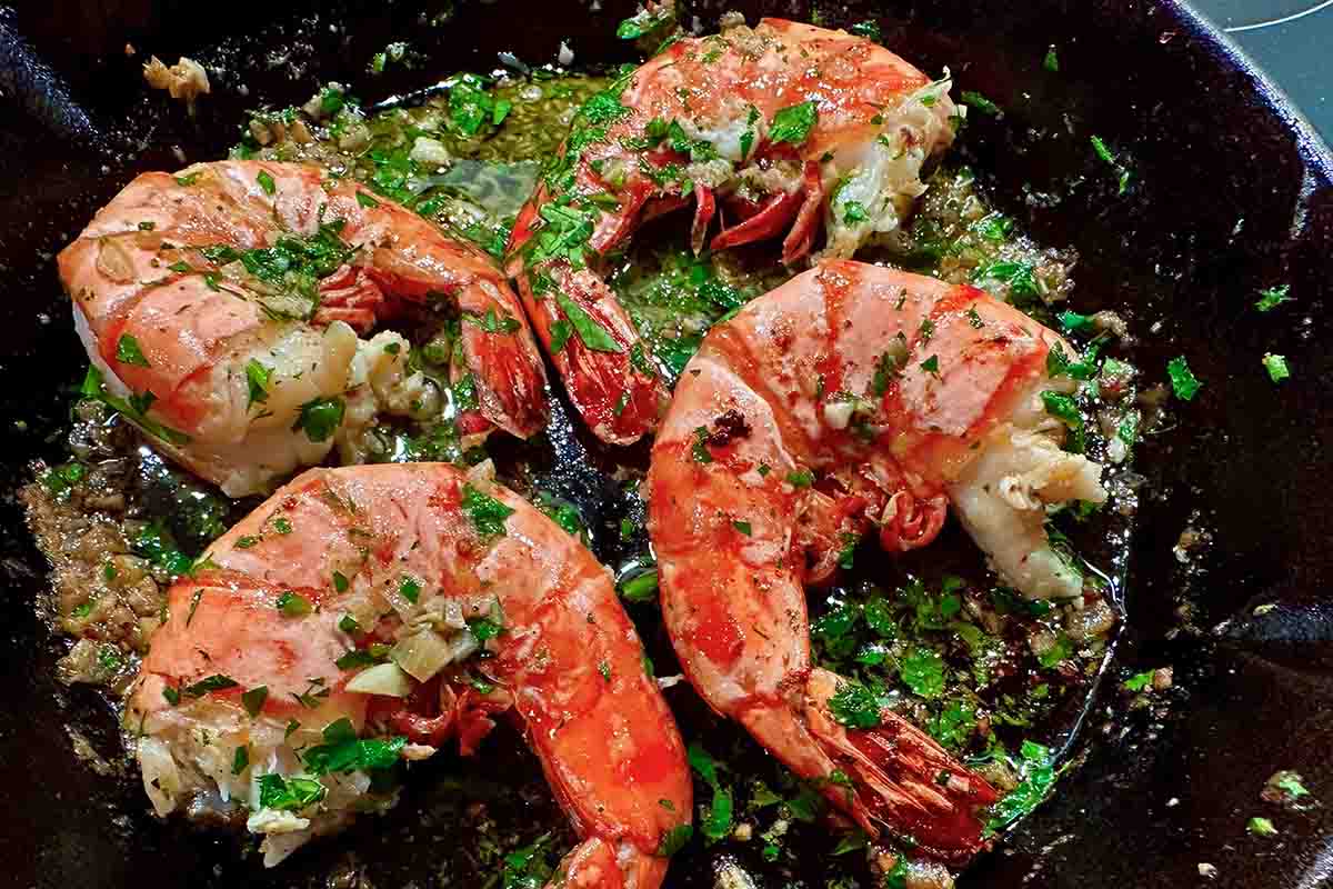 Garlic butter shrimp scampi in a cast-iron skillet, topped with fresh parsley and simmered in a flavorful, garlicky sauce.