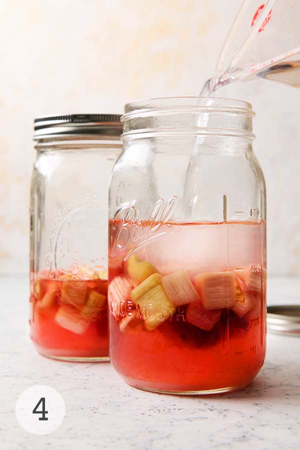 Vodka being poured into a mason jar of sugared rhubarb to start four-week steep.