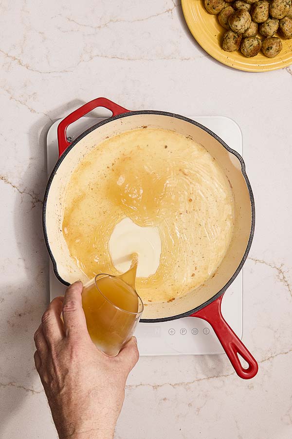 Chicken stock poured into pan of deglazed wine for piccata sauce.