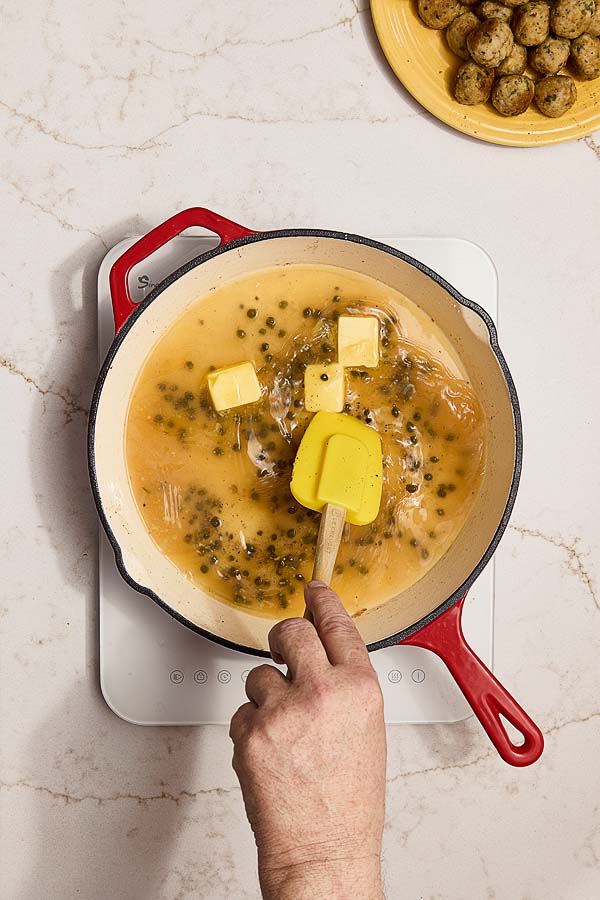 Capers and butter stirred into sauce for chicken piccata meatballs.