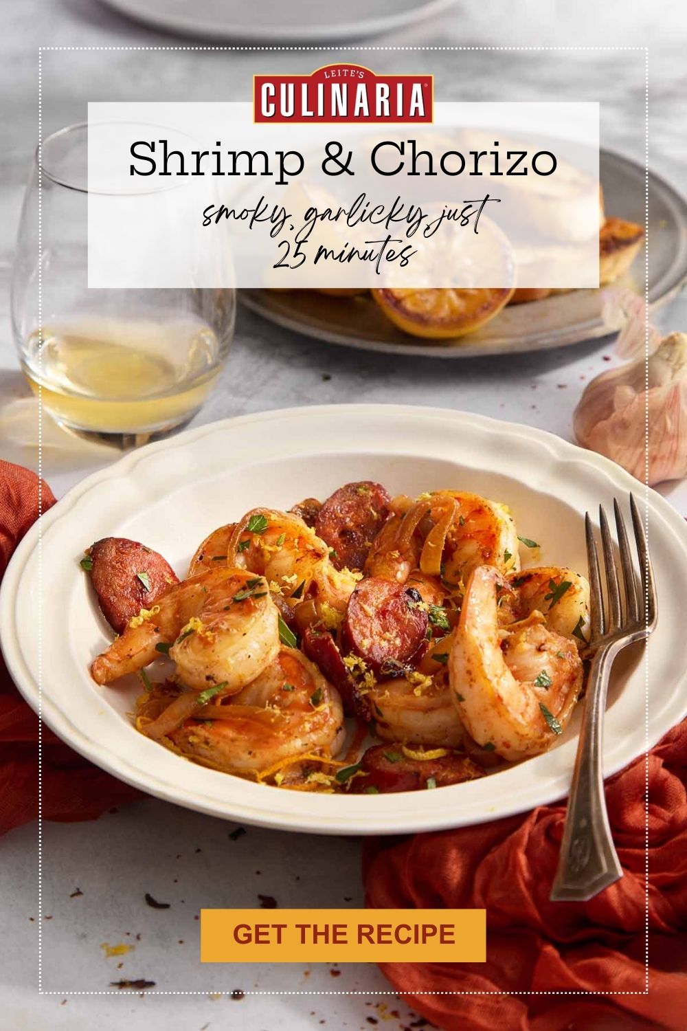 Shrimp and chorizo served in a bowl with parsley, garlic, and charred lemons in the background.