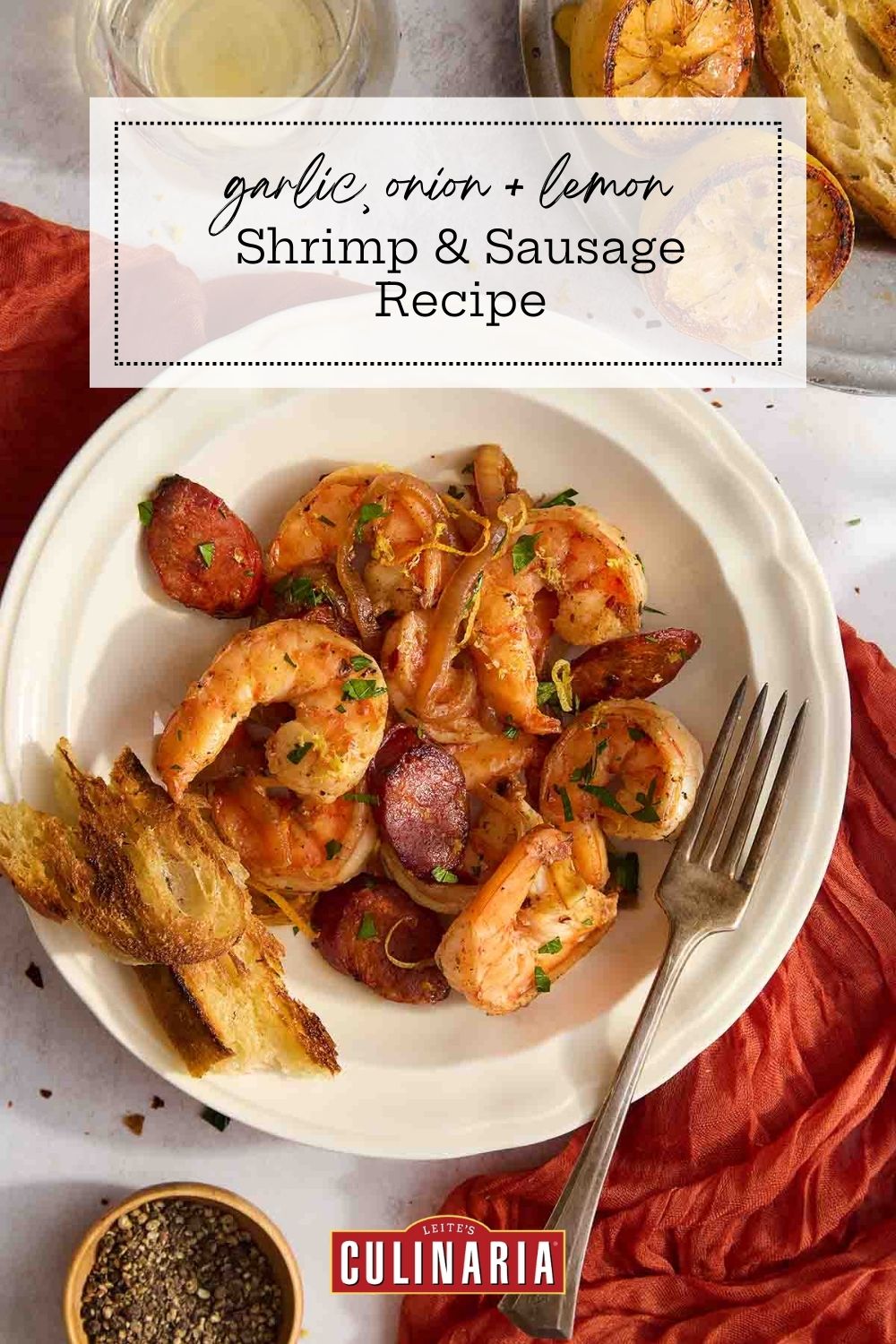 Overhead shot of shrimp and sausage with onions, lemon zest, and grilled bread on the side.