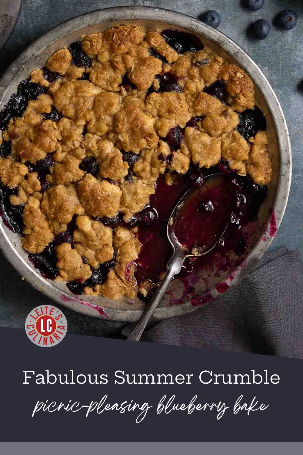 July 4th picnic blueberry crumble pin showing a full pan with a serving spoon.
