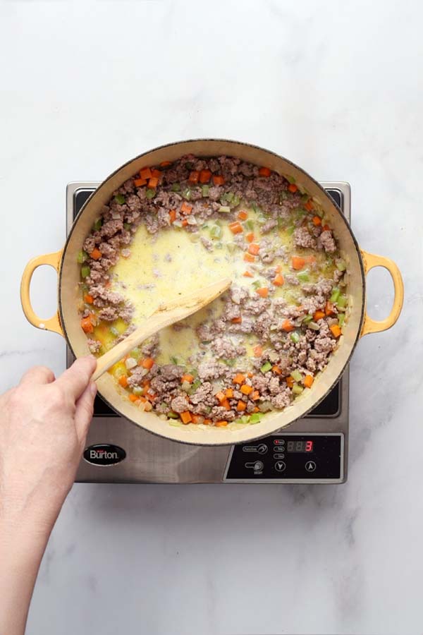 Whole milk added to the browned meat mixture, simmering gently until evaporated.