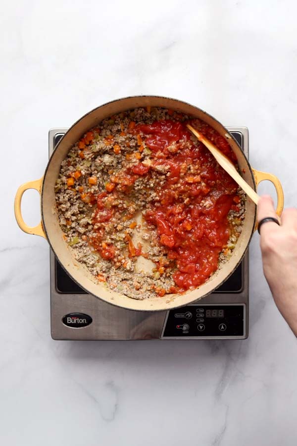 Crushed San Marzano tomatoes added to the Bolognese base, beginning the long simmer.