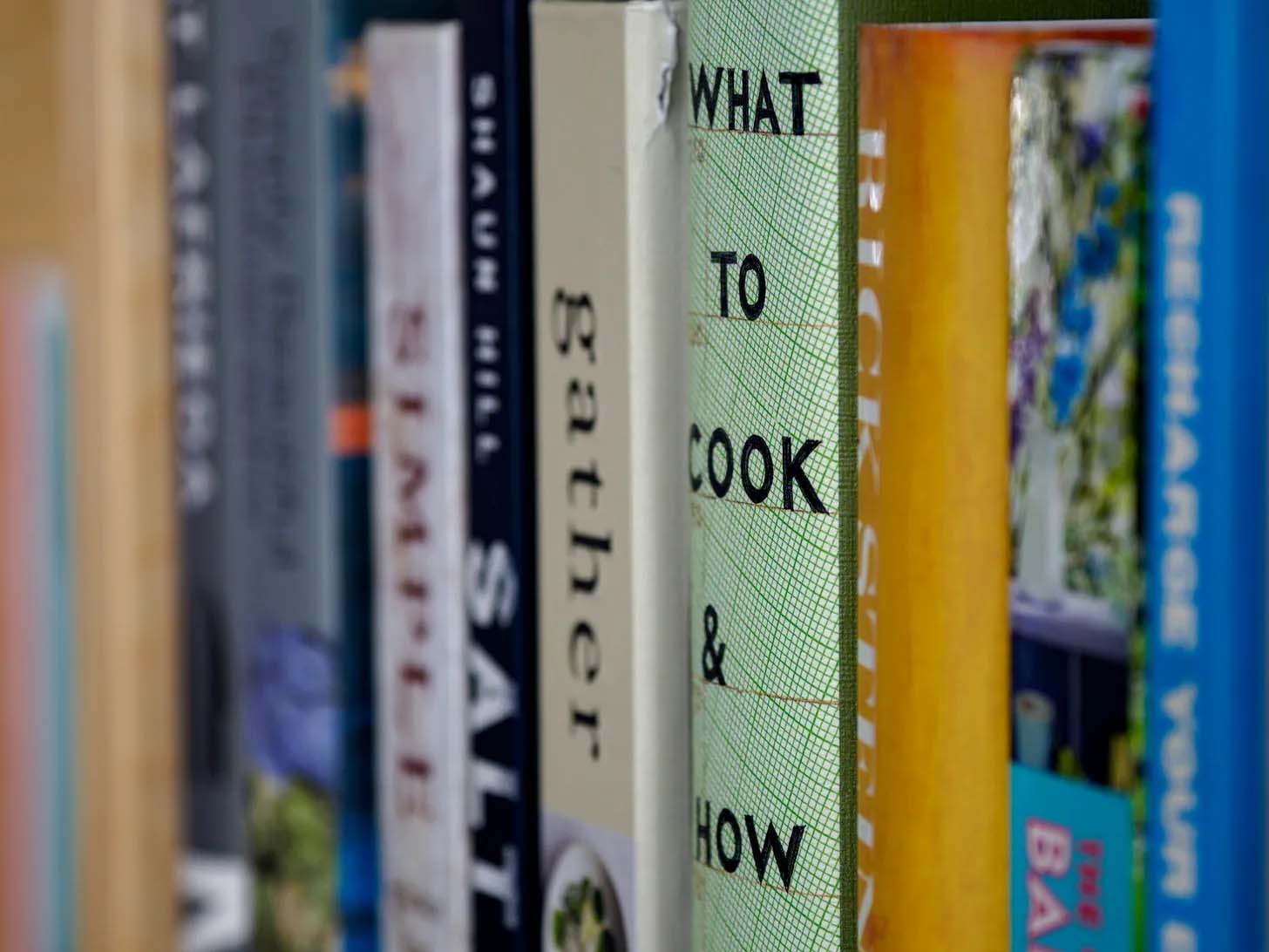 A row of cookbooks on a bookshelf.