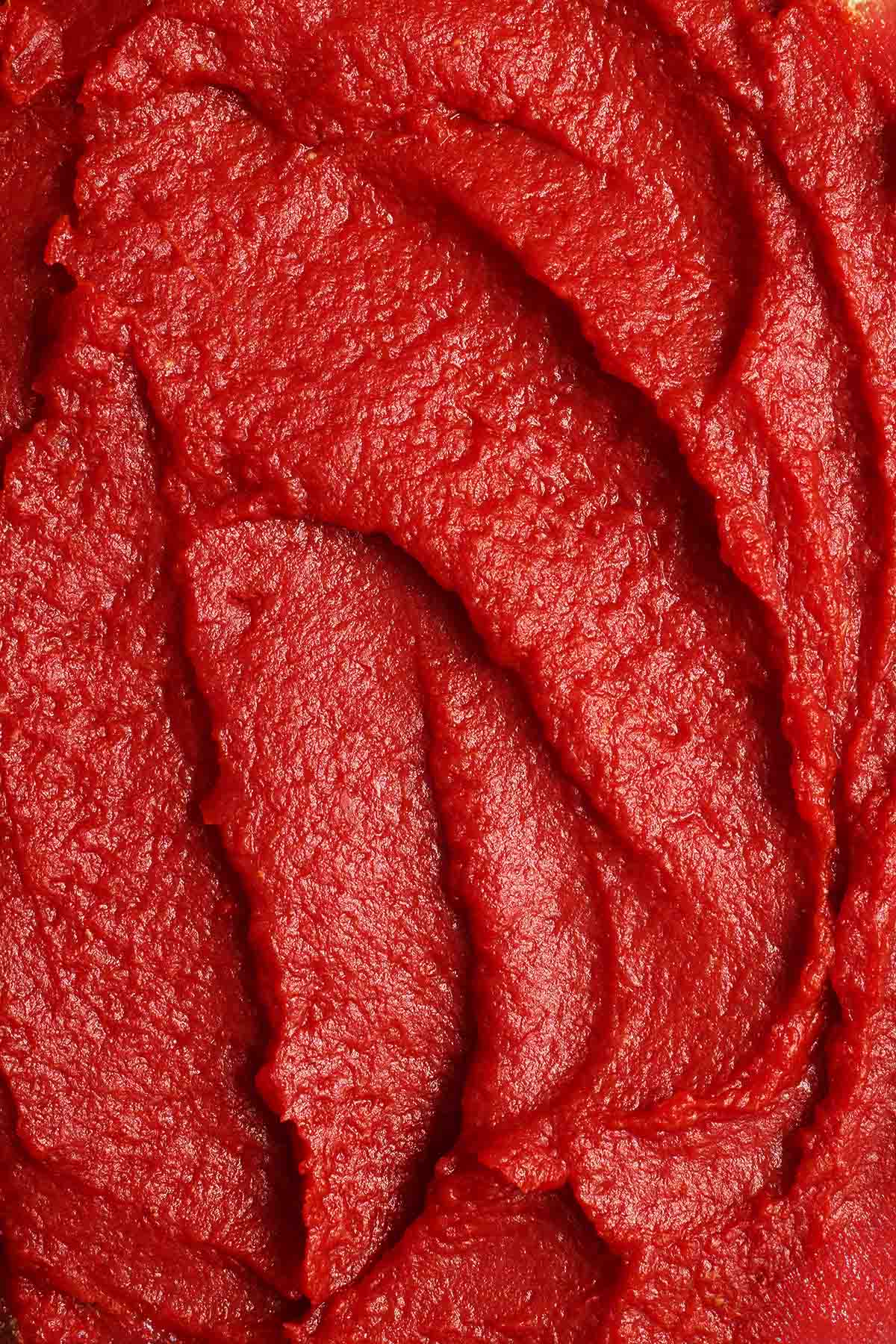 Rich, thick homemade tomato paste showing its deep red color and texture.