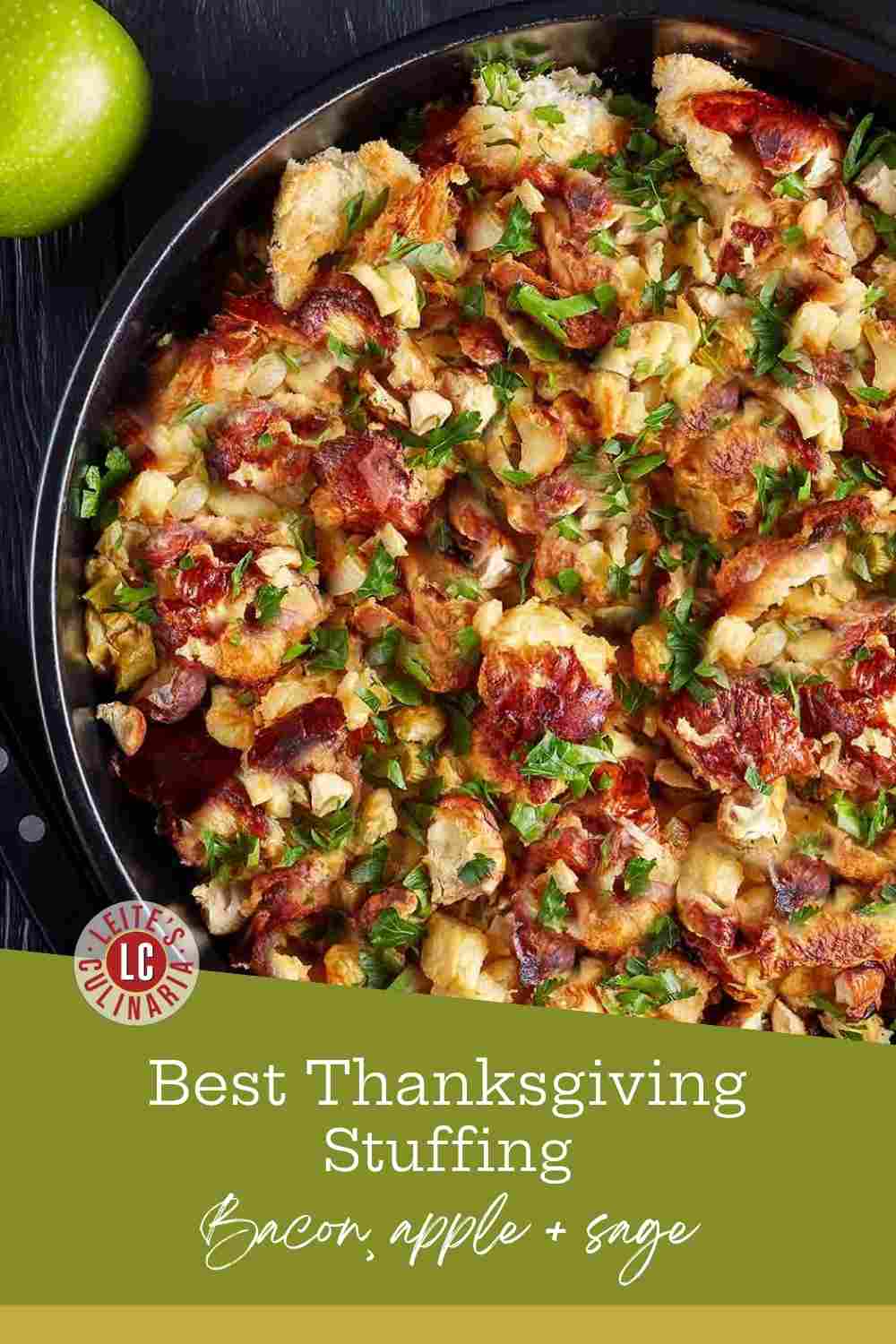 Holiday stuffing with bread cubes, fresh sage, crispy bacon, and diced apples in a black bowl.
