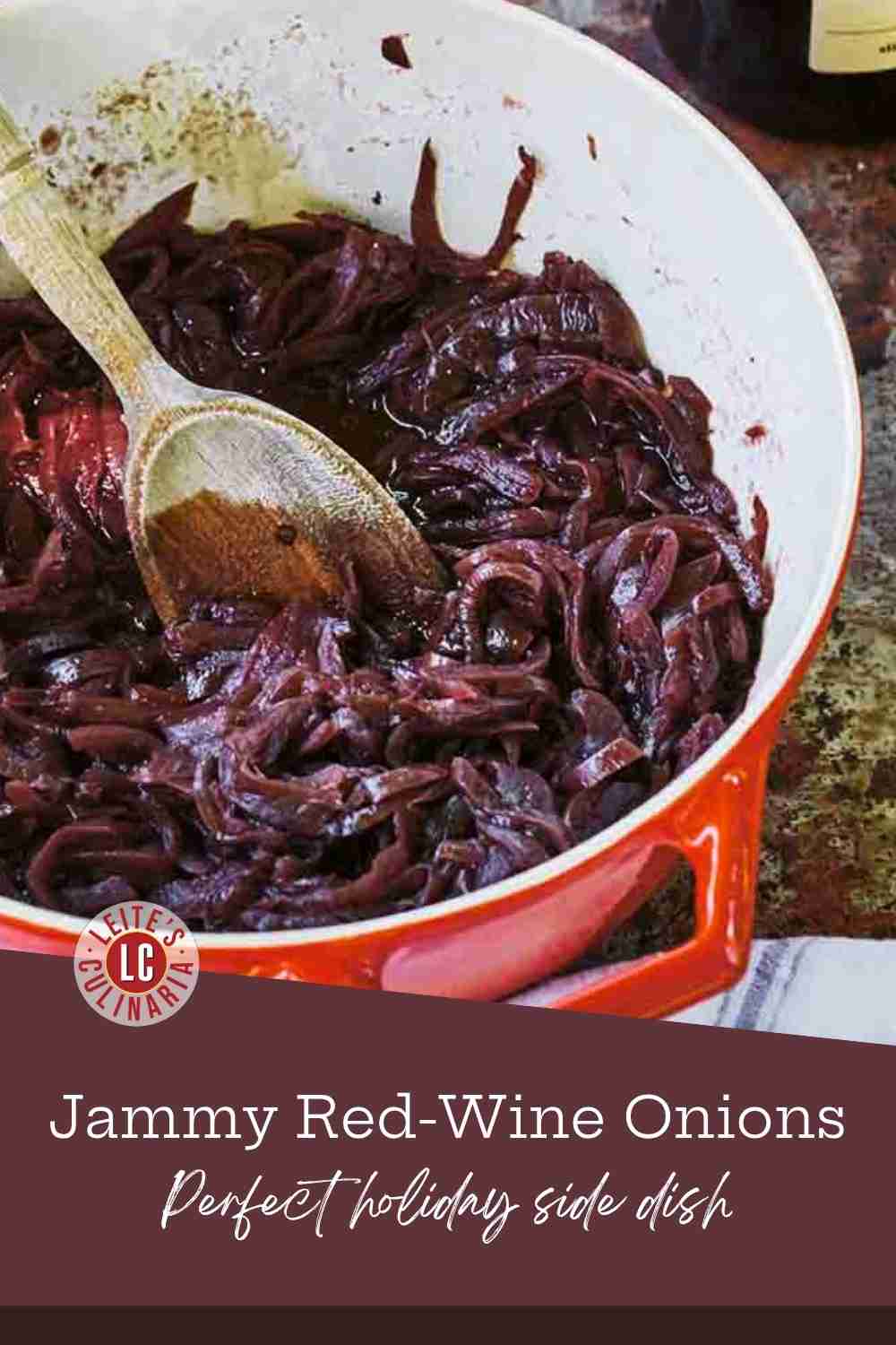 Close-up of glossy, deep purple-red caramelized onions in a small white pot with a wooden spoon, next to fresh red onion halves.