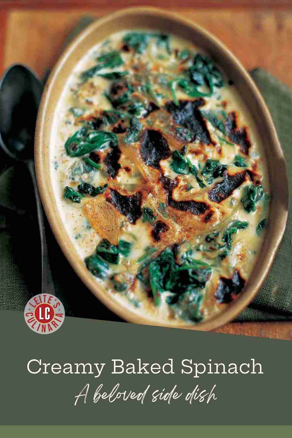 A ceramic oval dish of baked spinach mornay with cream sauce, sliced onion, and browned top.