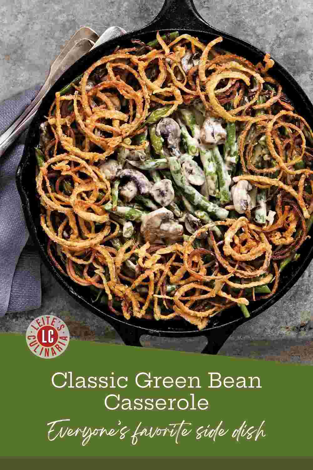 A cast iron skillet filled with green bean casserole topped with a golden, crunchy layer of fried onions.