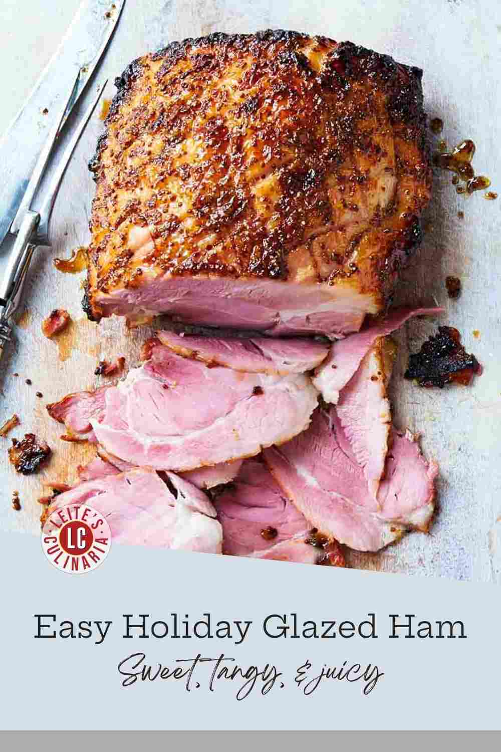 Baked boneless ham with a sticky brown sugar and orange marmalade glaze, sliced for serving on a white-washed board.