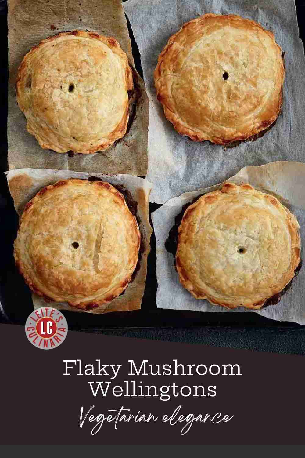 Four individual, round mushroom wellingtons with a golden-brown puff pastry crust cooling on a baking sheet lined with parchment.