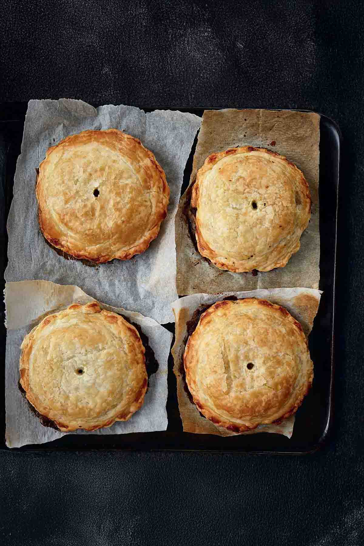 Four individual mushroom wellingtons with spinach and walnuts on a squares of parchment paper.