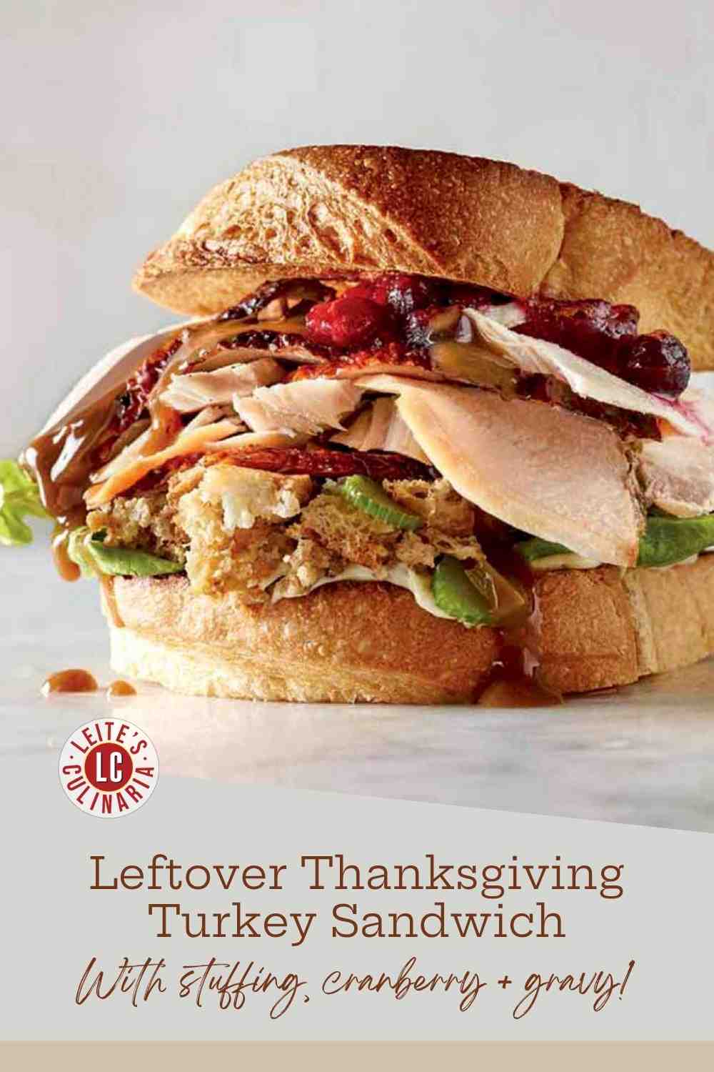 A turkey, cranberry, and stuffing sandwich with warm gravy drizzled over the savory filling.