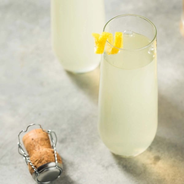 lose-up of a bubbly French 75 cocktail topped with a fresh lemon twist.