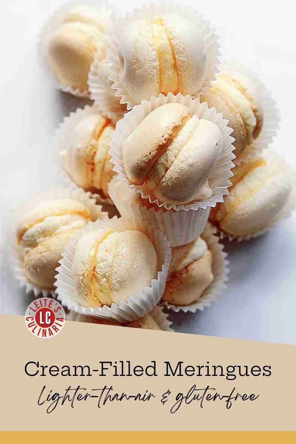 A stack of delicate, cream-filled meringue sandwich cookies, each one nestled in a white fluted paper cup.