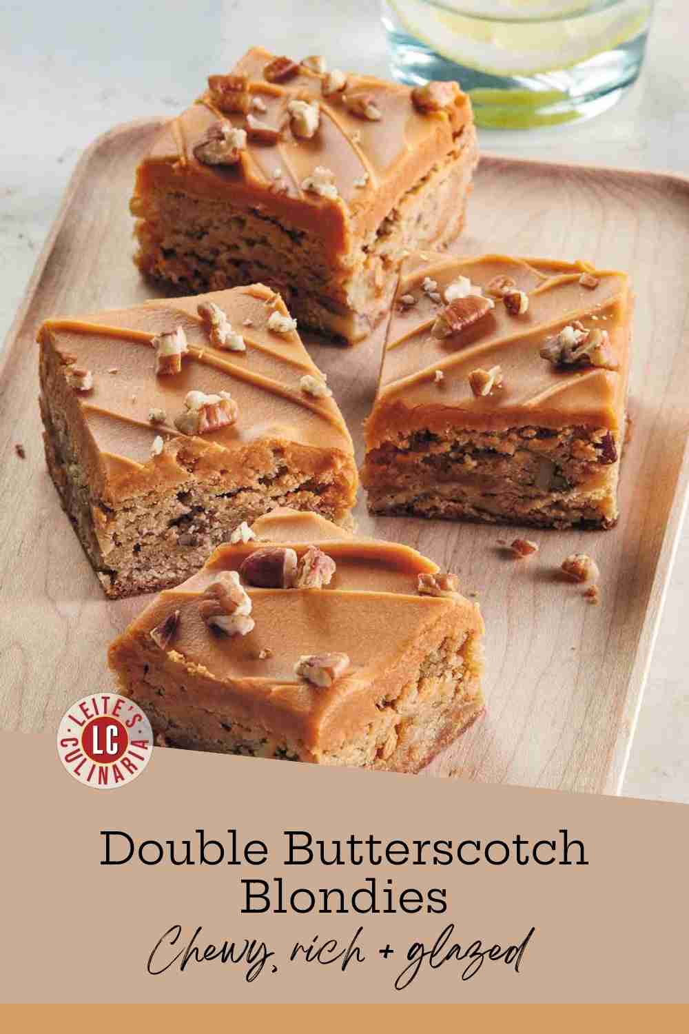 Four glazed butterscotch blondie squares topped with chopped pecans, served on a natural wood platter.