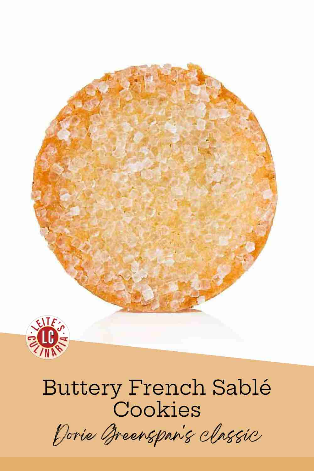 A single, golden brown French sablé cookie dusted with large crystal sanding sugar on a white background.