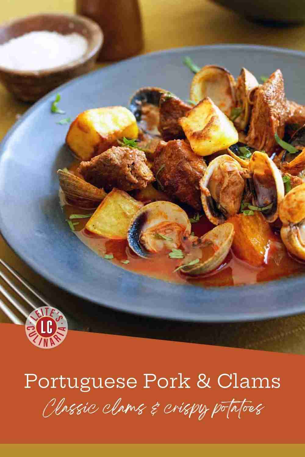 Succulent braised pork and fresh clams in a blue bowl with golden roasted potatoes and cilantro.