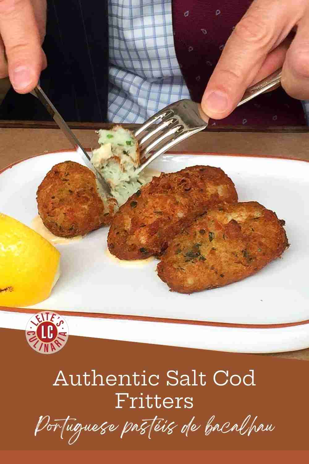 Close up of golden-brown salt cod fritters on a white plate with a lemon wedge and fork.