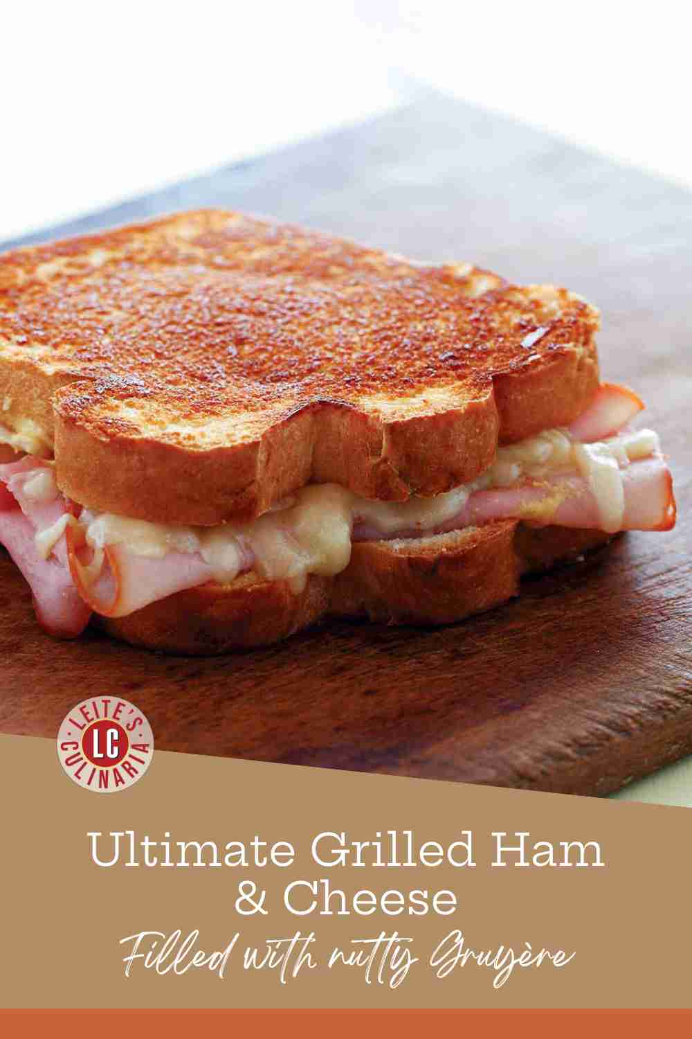 A toasted ham and cheese sandwich on thick white bread with melted Gruyere oozing from the sides.