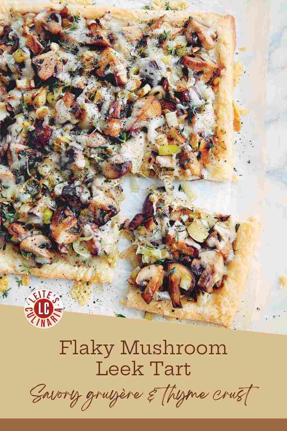 Sliced mushroom and leek tart on parchment paper with golden puff pastry crust and melted Gruyère cheese.