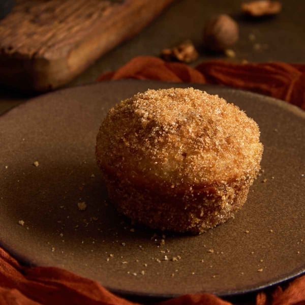 Close up of a baked dirt bomb muffin heavily coated in cinnamon sugar and melted butter.