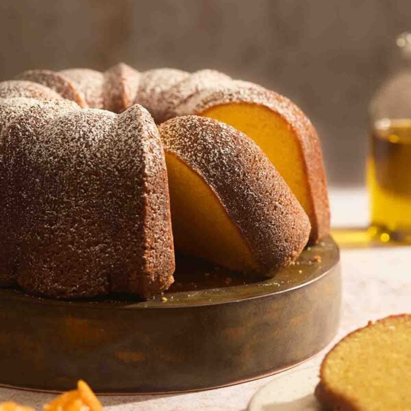 Close up shot of a moist orange olive oil cake slice showing a tender crumb and golden crust.